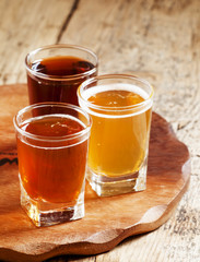 Three kinds of beer on old wooden background, selective focus