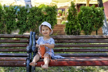 trendy little girl sitting on a wood bench with her handbag