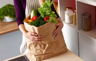 Assorted fruits and vegetables in brown grocery bag holding a