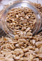 Sunflower seeds spilling out of glass jar. Wooden background