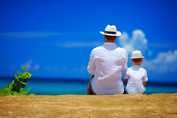 rear view of father and son sitting together on sky horizon