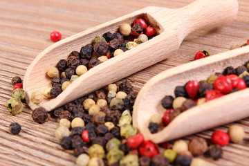 Fresh colored pepper with spoon on wooden background