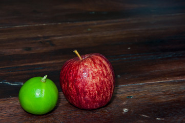 Apple and lemon on wooden desk.