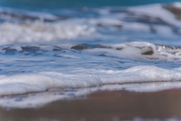Fototapeta na wymiar Waves on the sandy beach with bubbles