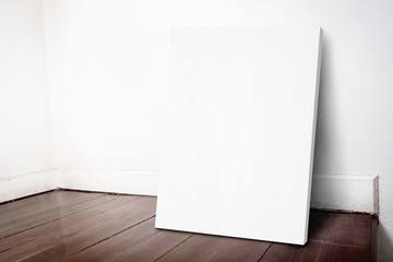 Blank white canvas frame leaning at grunge house wall and dark b