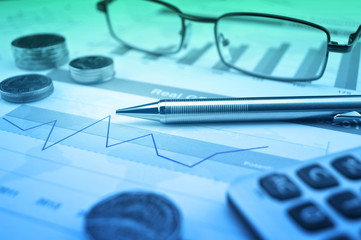 Pen, gasses, coin and calculator on financial chart and graph, a