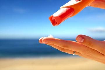 Woman hands putting sunscreen from a suncream bottle