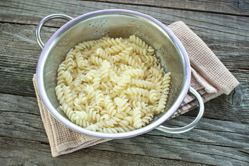 Fresh cooked fusilli pasta in strainer on table
