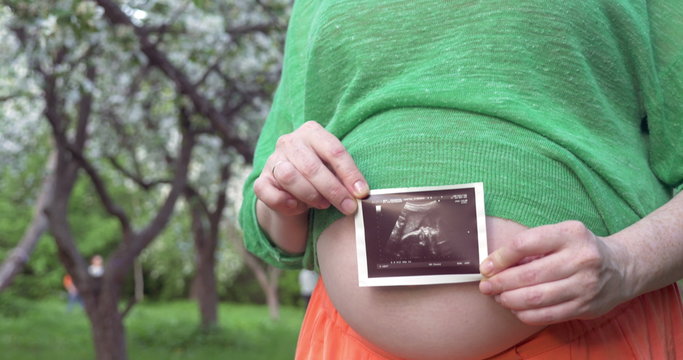Pregnant woman with baby ultrasound scan outdoor