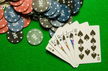 Playing cards 'royal flush' and chips on green background