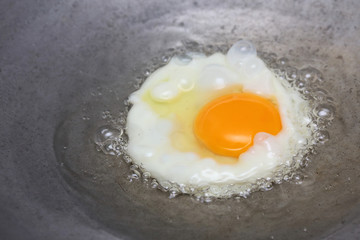 cooking fried egg in hot pan with oil