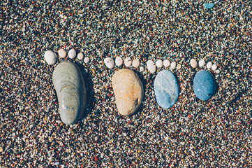 trace bare feet made of pebble stones on the beach coast sand to