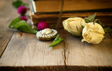 Fototapeta na wymiar selective focus image of dry rose, antique necklace and old vintage books