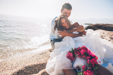 Bride and groom on the beach on their wedding day - obrazy, fototapety, plakaty