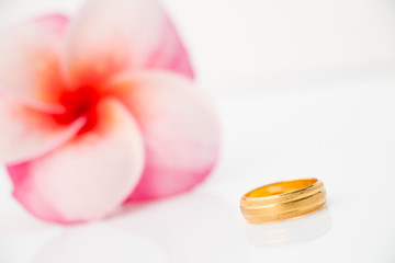 Obraz na płótnie Canvas wedding ring with Plumeria flower on white bakcground (Love concept)