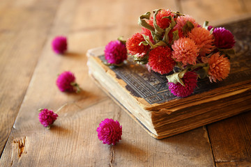 selective focus image of dry flowers, antique necklace and old vintage books