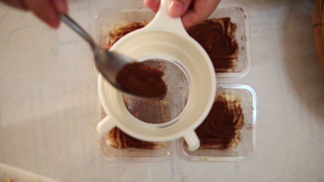 Dusting tiramisu cake by powdered cocoa