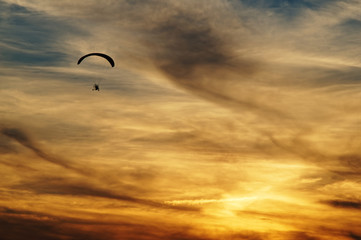 Paragliding in clouds at sunset. Silhouette against a background a cloudy sky colors the sunset.