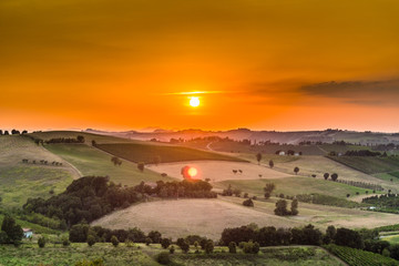 sunset on lush farmland in hilly countryside