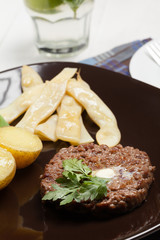 Grilled hamburger with potatoes and yellow beans.