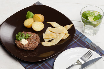 Grilled hamburger with potatoes and yellow beans.