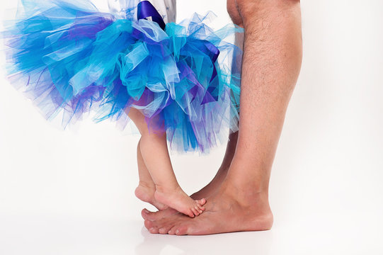 Bare baby and dad feet with tutu