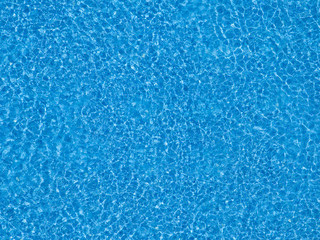 Water ripples on blue tiled swimming pool background.