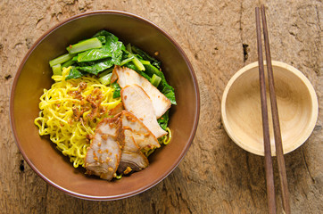 Yellow noodles served with sliced pork