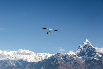 Ultra light plane flying over the Annapurna mountain range in the Himalayas near Pokhara, Nepal. The summit on the right is the Machapuchare (6993m), aka the fishtail mountain.