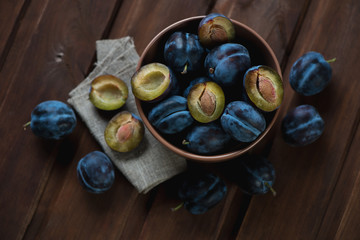 Above view of ripe plums over dark brown wooden background