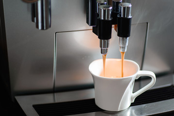 Close up of espresso coffee machine dispensing coffee into a coffee cup