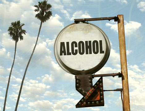 aged and worn vintage photo of alcohol sign with arrow and palm trees