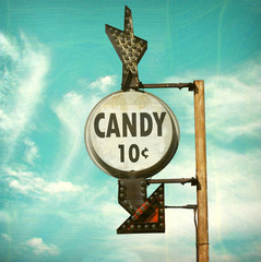 aged and worn retro photo of candy ten cents sign with bulbs and arrow