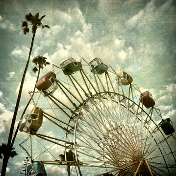aged and worn vintage photo of ferris wheel and palm trees