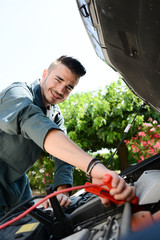 handsome young man car mechanic checking a car engine breakdown outdoor