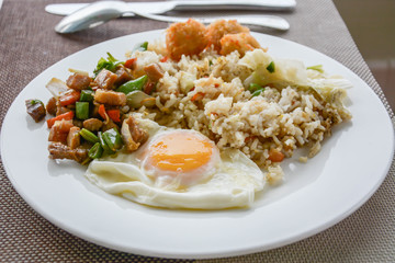 Chinese fried rice with vegetables, chicken and fried eggs served on a plate with chopsticks