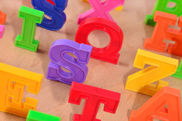 Plastic colorful letters close up on a wooden background