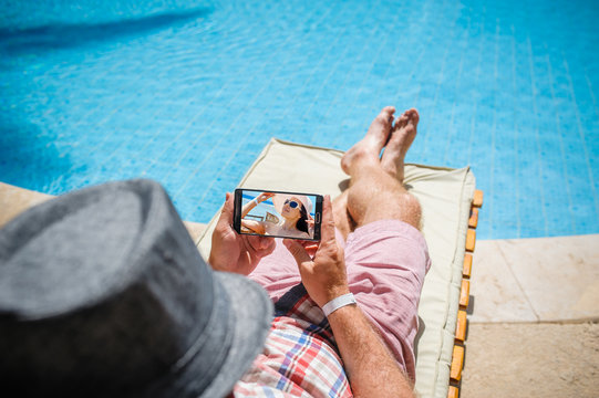 man in a hat lying on a lounger with a smartphone