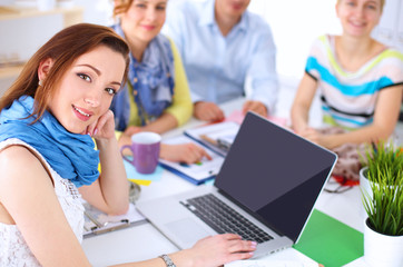 Portrait of attractive female  designer sitting on desk  in