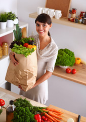 Young woman holding grocery shopping bag with vegetables