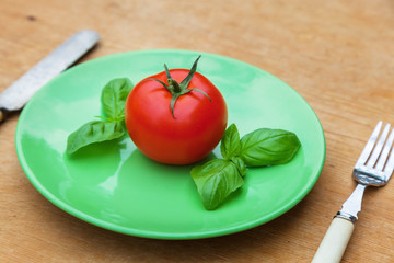 Tomate mit Basilikum auf grünem Teller