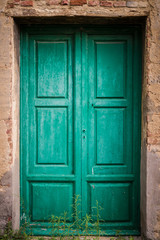 Fototapeta na wymiar Green door at Toiano, little ghost town in Tuscany, Italy