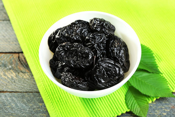 Saucer of prunes with leaves on green napkin, closeup