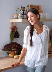 Young woman standing near desk in the kitchen