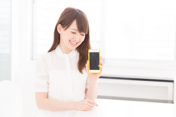 Fototapeta premium 部屋でスマホの画面を見せる女性