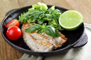 Dish of fish fillet with salad and lime on table close up