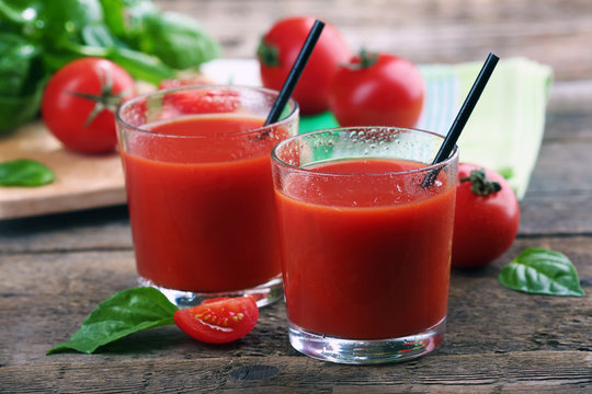 Glasses of tomato juice on wooden table, closeup