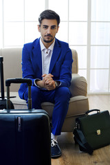 Business man with suitcases sitting on sofa in hall