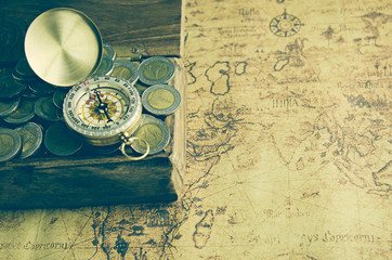 Vintage compass and coins on old map