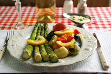 Roasted asparagus and tasty colorful pasta with vegetables on plate on wooden table background
